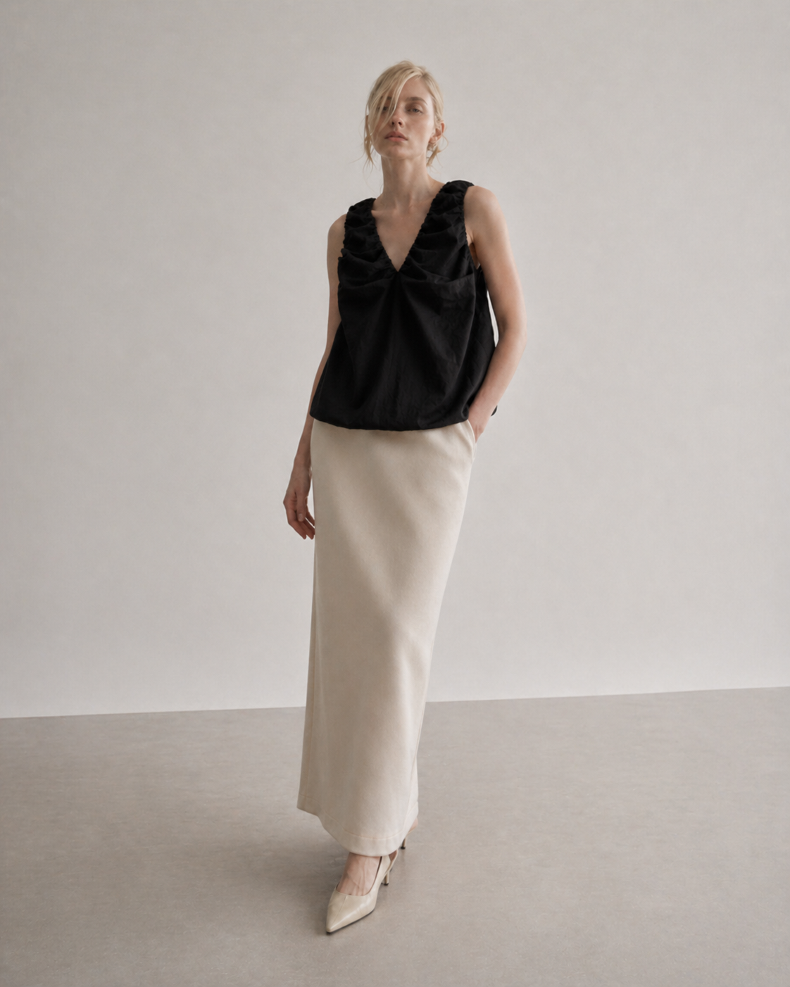 Woman wearing a black sleeveless top and beige pants