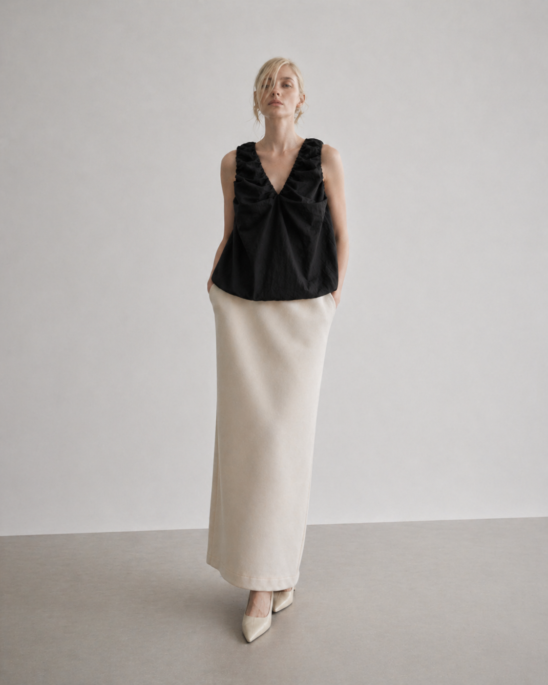 ledair wearing a black sleeveless top and beige skirt 