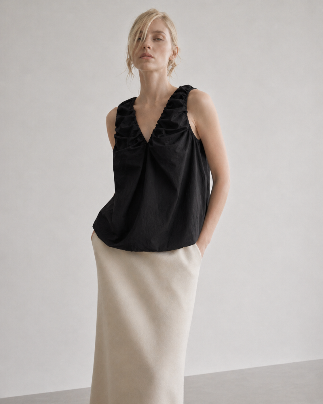 Woman wearing a black sleeveless top and beige skirt 